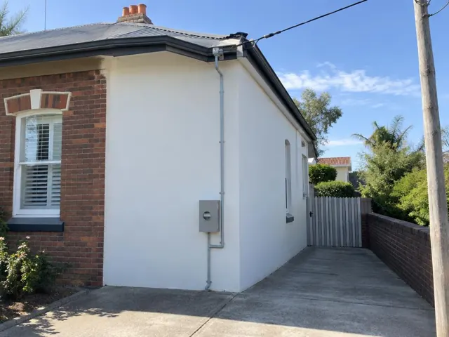 Overhead service cable and wall bracket on a brick and rendered house exterior in Clovelly